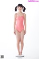 A young girl in a pink swimsuit standing on a scale.