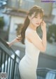 A woman in a white dress standing on a balcony.