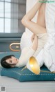 A woman laying on top of a bed next to a lamp.