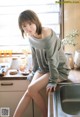 A woman sitting on a kitchen counter next to a sink.