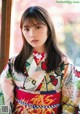 A woman in a colorful kimono poses for a picture.