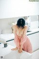 A woman in a pink dress sitting on a kitchen counter.