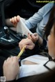 A woman sitting in the driver's seat of a car holding a piece of paper.