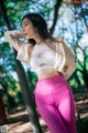 A woman in a white top and pink leggings posing for a picture.