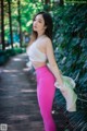 A woman in a white top and pink leggings posing for a picture.