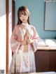 A woman in a pink and white kimono posing on a bed.