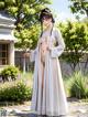 A woman in a white kimono standing in a garden.