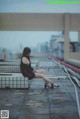 A woman sitting on a bench with her legs crossed.