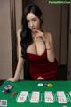 A woman in a red dress sitting at a poker table.