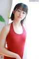 A woman in a red tank top posing for a picture.