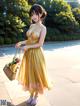 A woman in a yellow dress holding a basket of flowers.