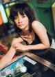 A woman sitting at a table with a pinball machine.