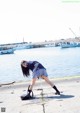 A woman in a school uniform bending over to pick up something.