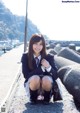 A woman in a school uniform sitting on the ground.