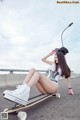 A woman sitting on a skateboard on the side of a road.